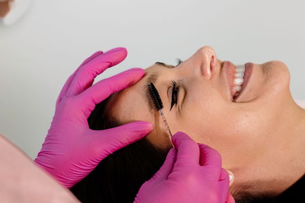 Eyebrow grooming in progress with gloved hands