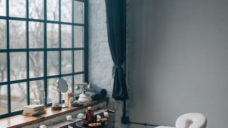 Treatment room with a massage table beside a tall window and a folded towel