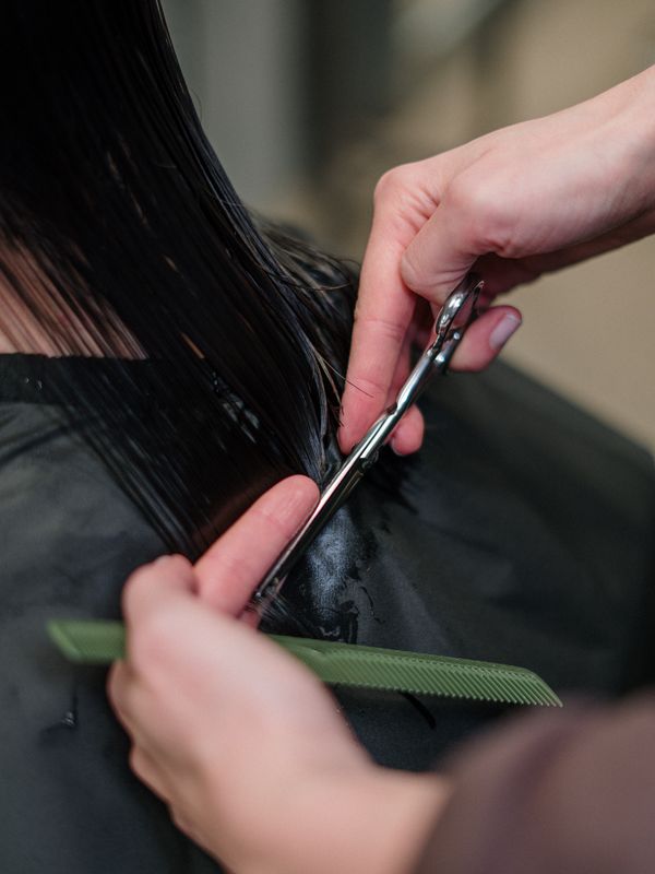 A client mid-haircut, cape on, under studio lighting