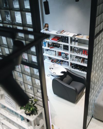 A single backwash chair and sink in a small salon nook, product shelf behind